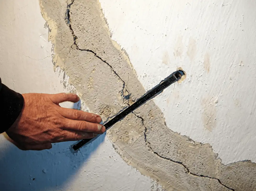 A wall with a large crack is being inspected by a professional in Sioux Falls, SD